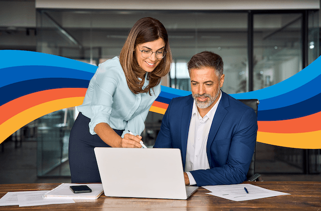 a man and a woman are looking at a laptop together